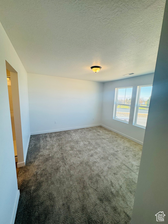 Carpeted spare room featuring baseboards and a textured ceiling