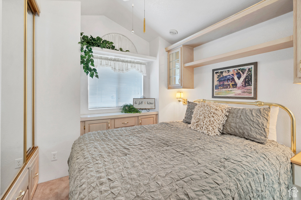 Bedroom with vaulted ceiling and light carpet
