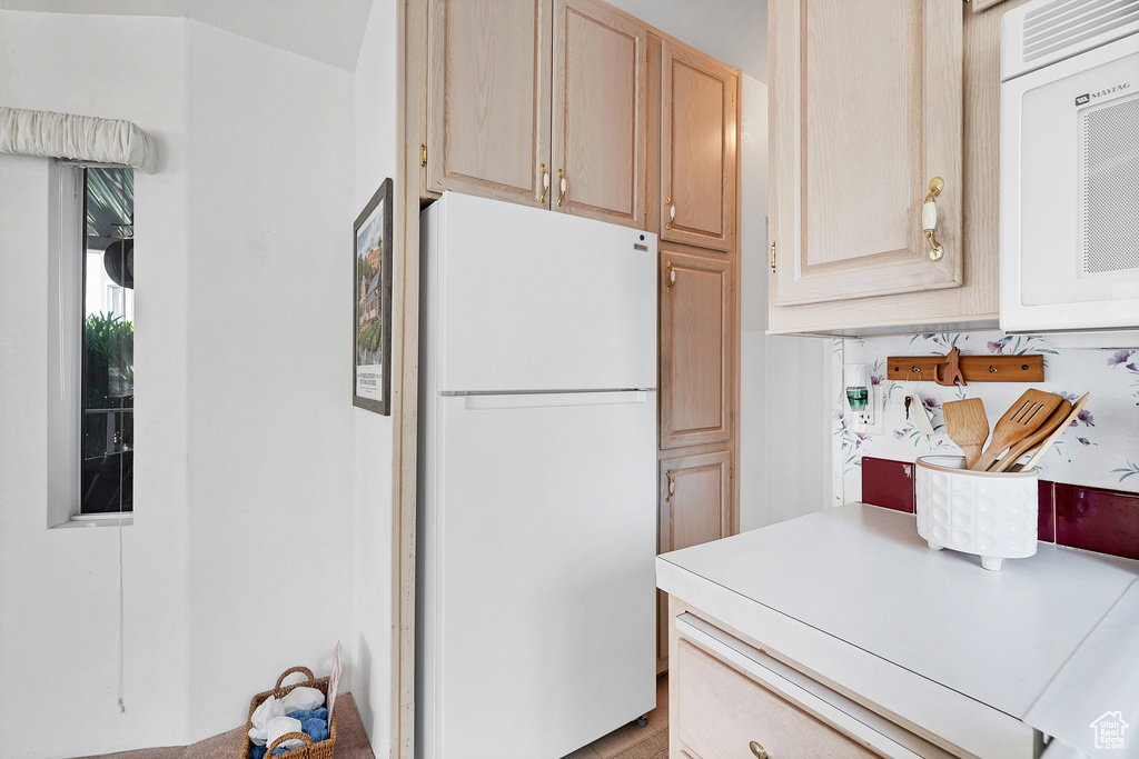 Kitchen featuring white appliances, light brown cabinets, and light countertops