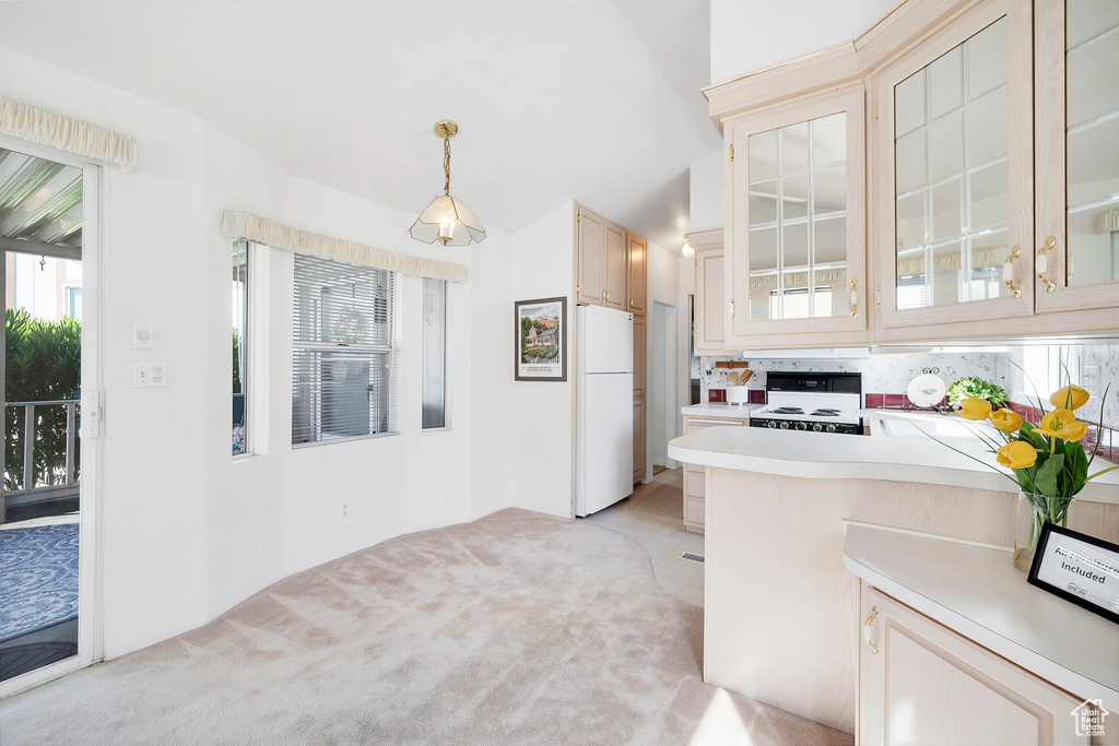 Kitchen with freestanding refrigerator, stove, light countertops, glass insert cabinets, and light carpet
