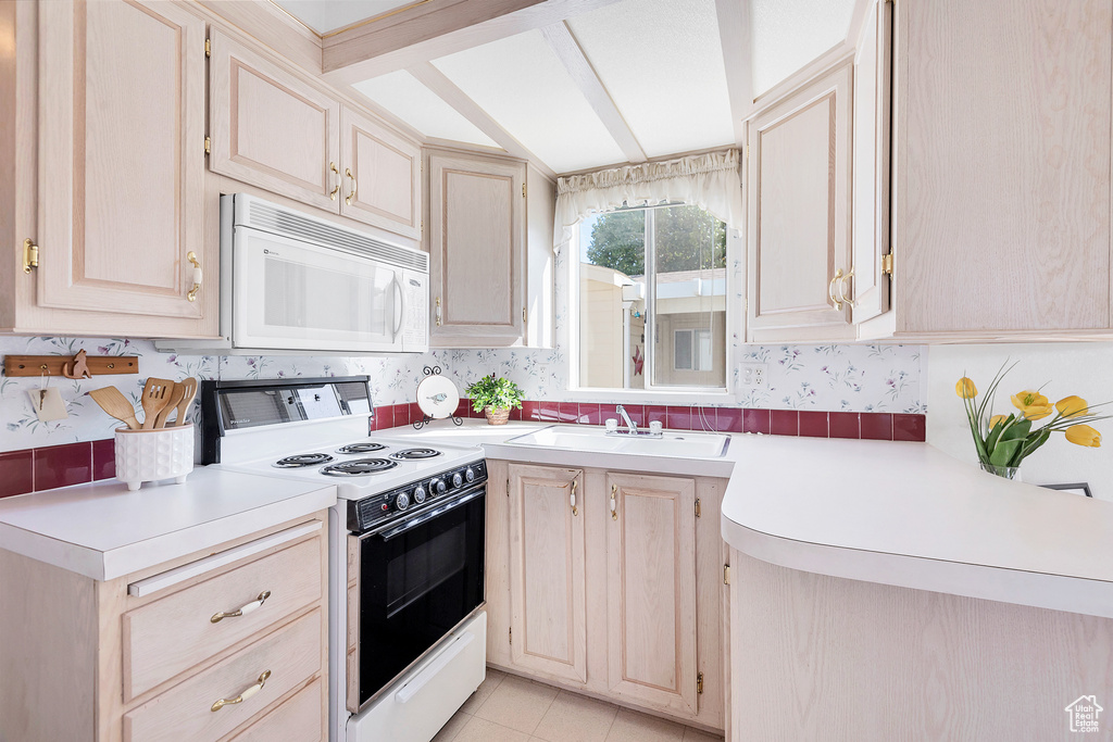 Kitchen featuring white appliances, light countertops, lofted ceiling, and light tile patterned floors
