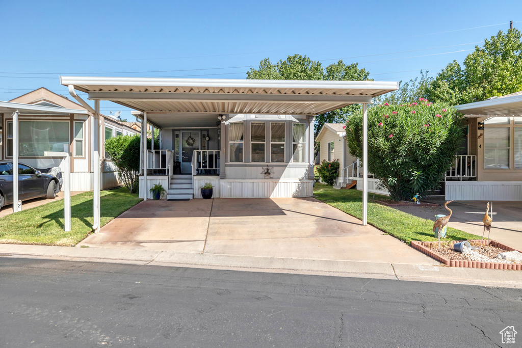 Manufactured / mobile home featuring a front yard, a carport, and covered porch