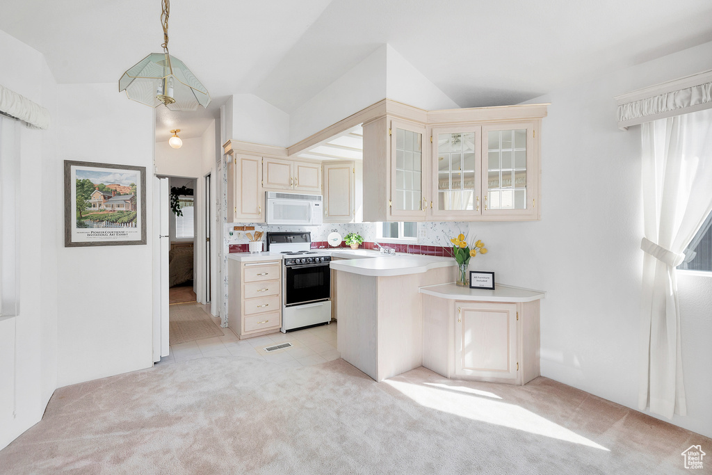 Kitchen featuring white appliances, cream cabinetry, light countertops, light carpet, and glass insert cabinets