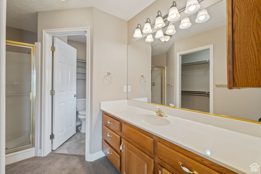 Full bath with a stall shower, vanity, and a walk in closet