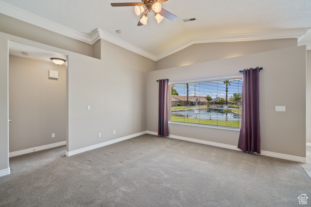 Spare room featuring a ceiling fan, carpet, crown molding, and lofted ceiling