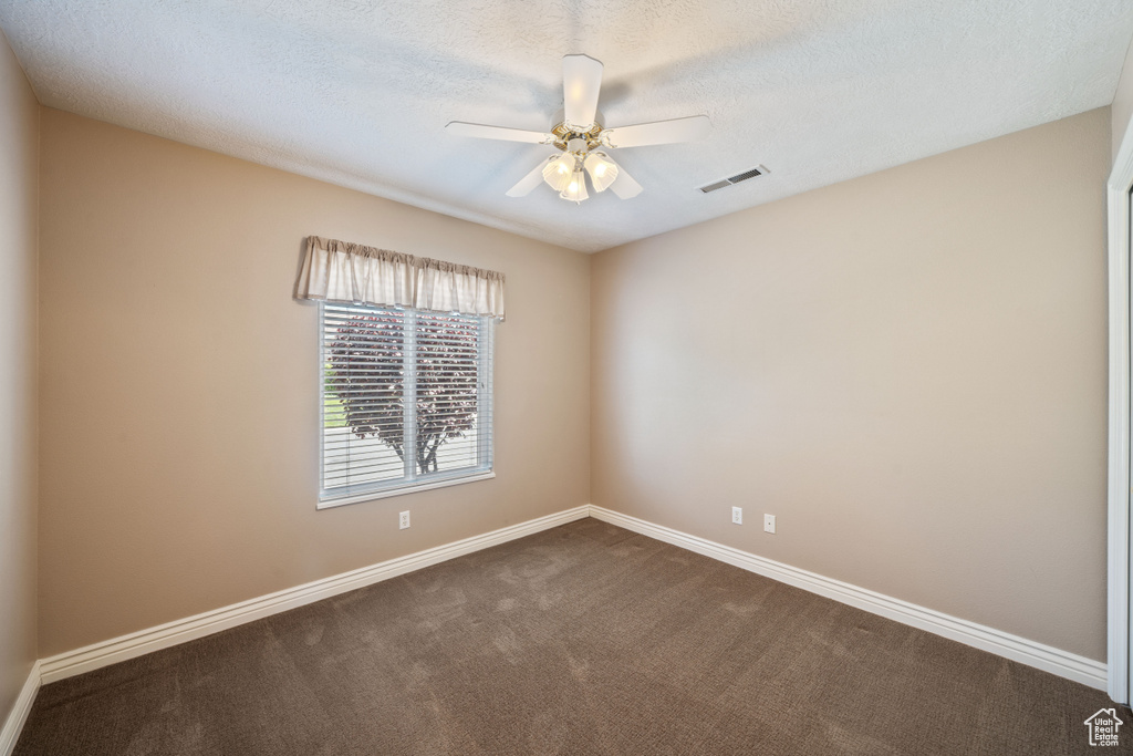 Unfurnished room with dark carpet and a ceiling fan