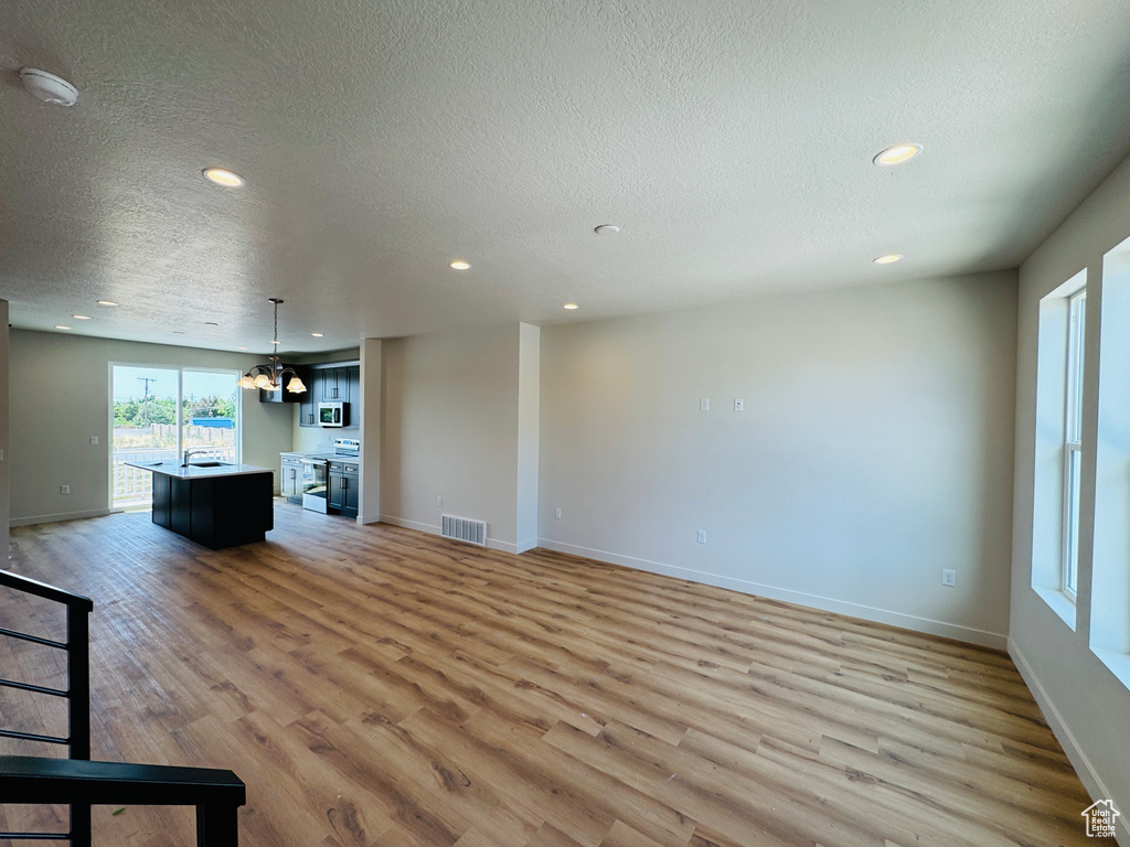 Unfurnished living room featuring light wood-type flooring, recessed lighting, and a textured ceiling