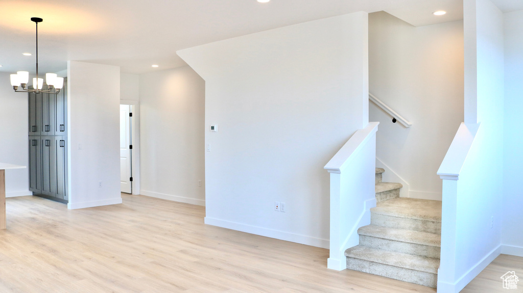 Stairway featuring wood finished floors, a chandelier, and recessed lighting