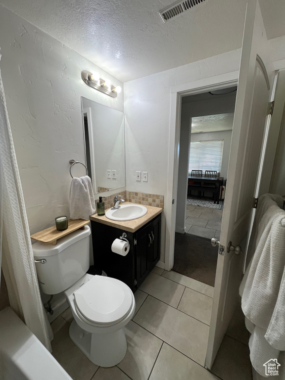 Bathroom with a textured ceiling, vanity, and tile patterned floors