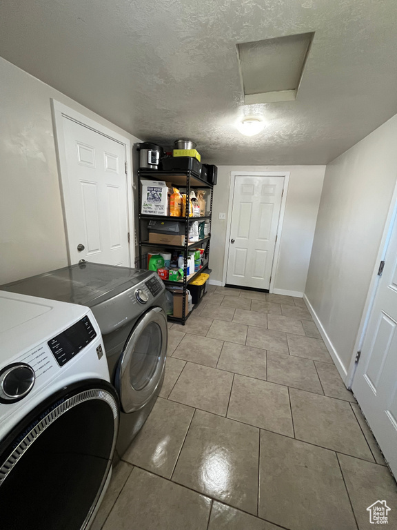 Laundry room with separate washer and dryer, attic access, tile patterned floors, and a textured ceiling