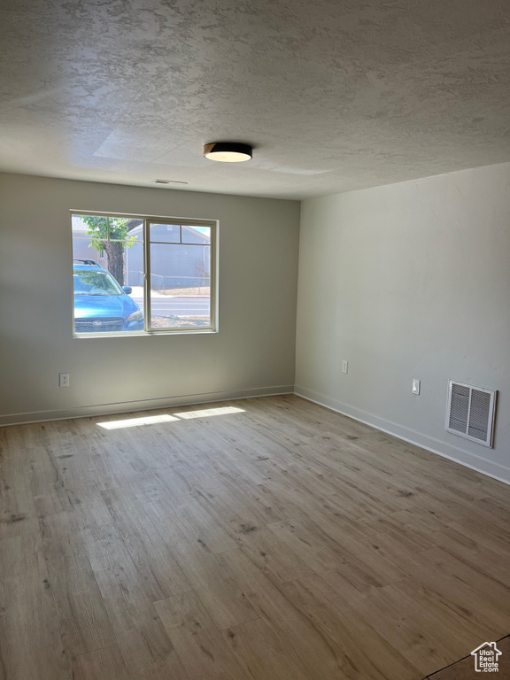 Spare room with wood finished floors and a textured ceiling