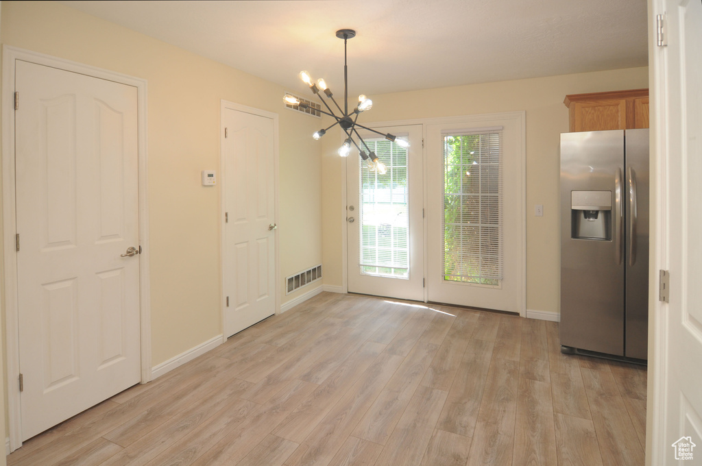 Unfurnished dining area with a chandelier and light wood finished floors