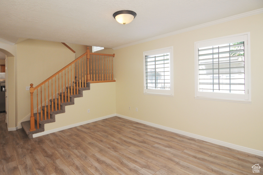 Basement featuring crown molding, wood finished floors, stairway, and arched walkways