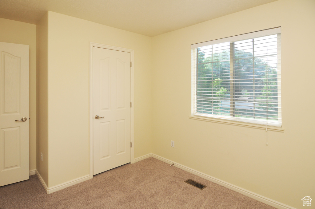 Unfurnished bedroom featuring light carpet and baseboards