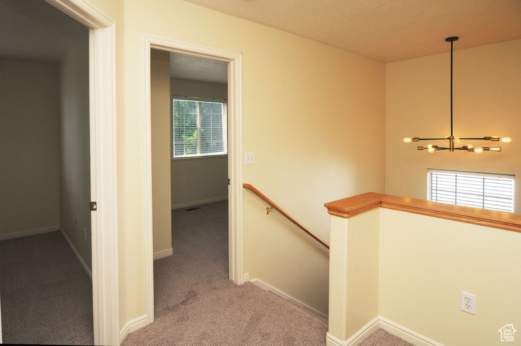 Corridor featuring an upstairs landing, a chandelier, and carpet floors