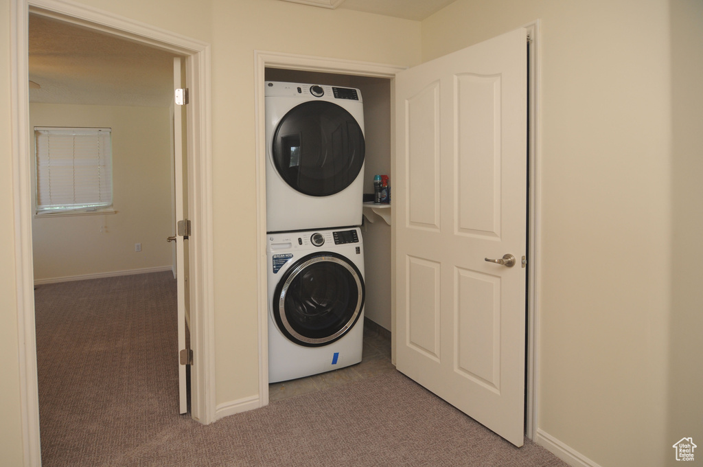 Washroom featuring stacked washer / dryer and carpet floors