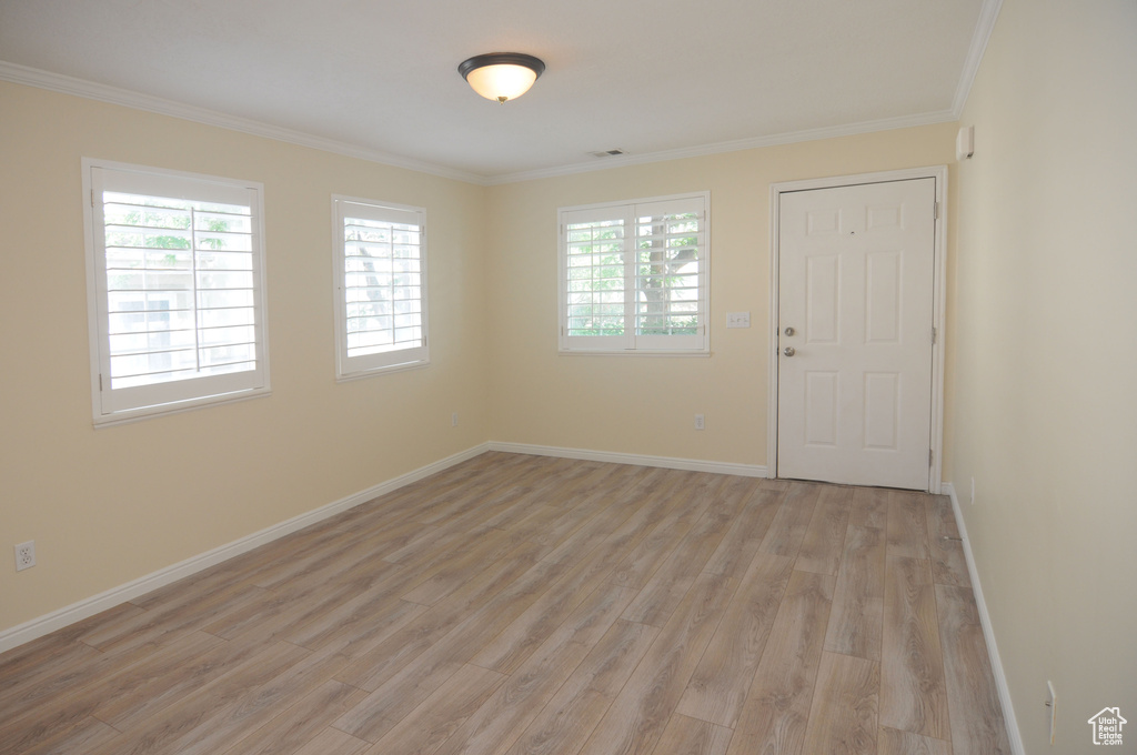 Entryway with light wood finished floors and ornamental molding