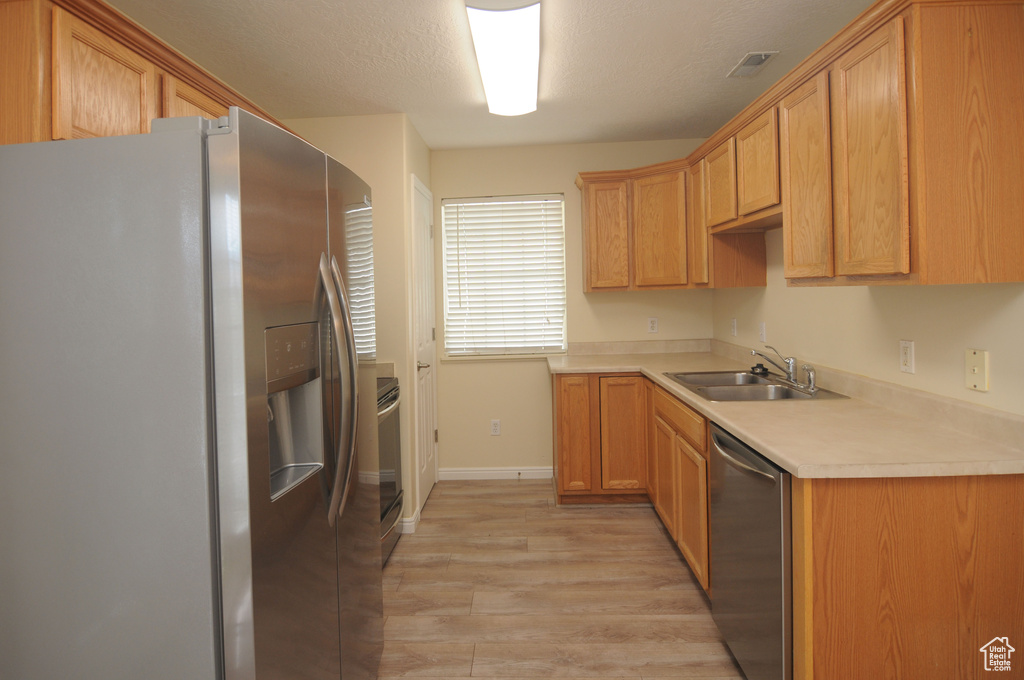 Kitchen with stainless steel appliances, light wood-type flooring, and light countertops