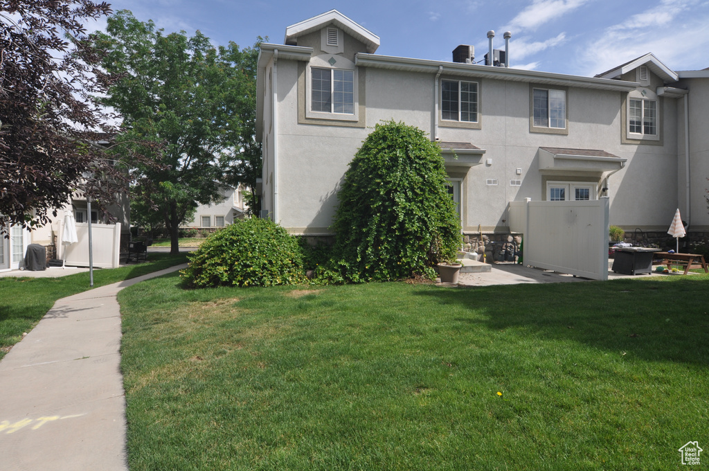 Rear view of house with stucco siding and a yard