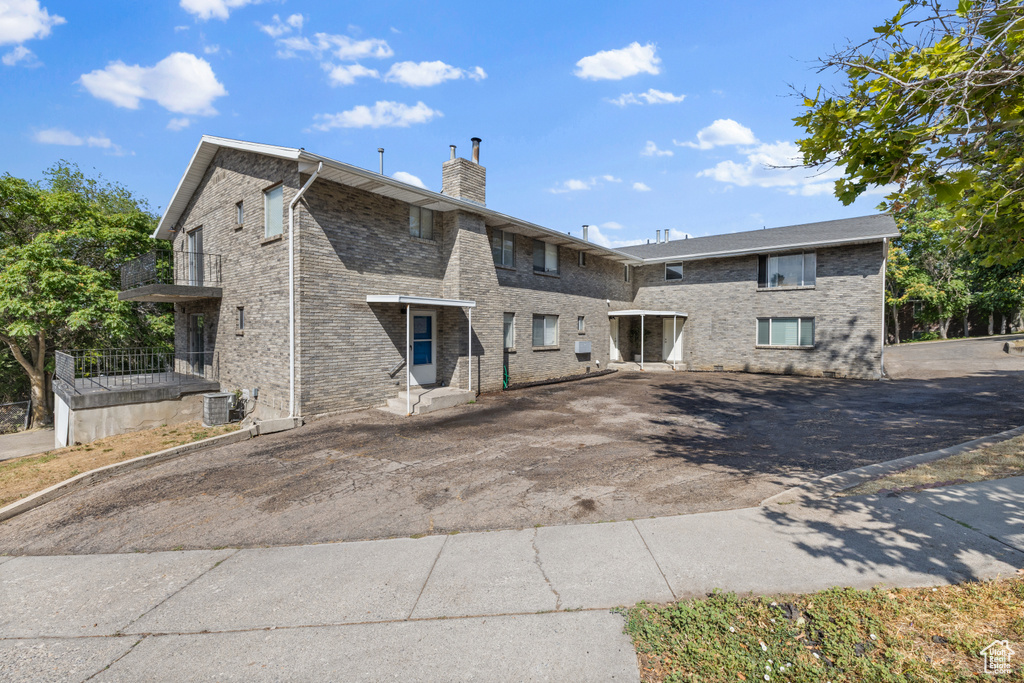 Rear view of property with a chimney, brick siding, and asphalt driveway