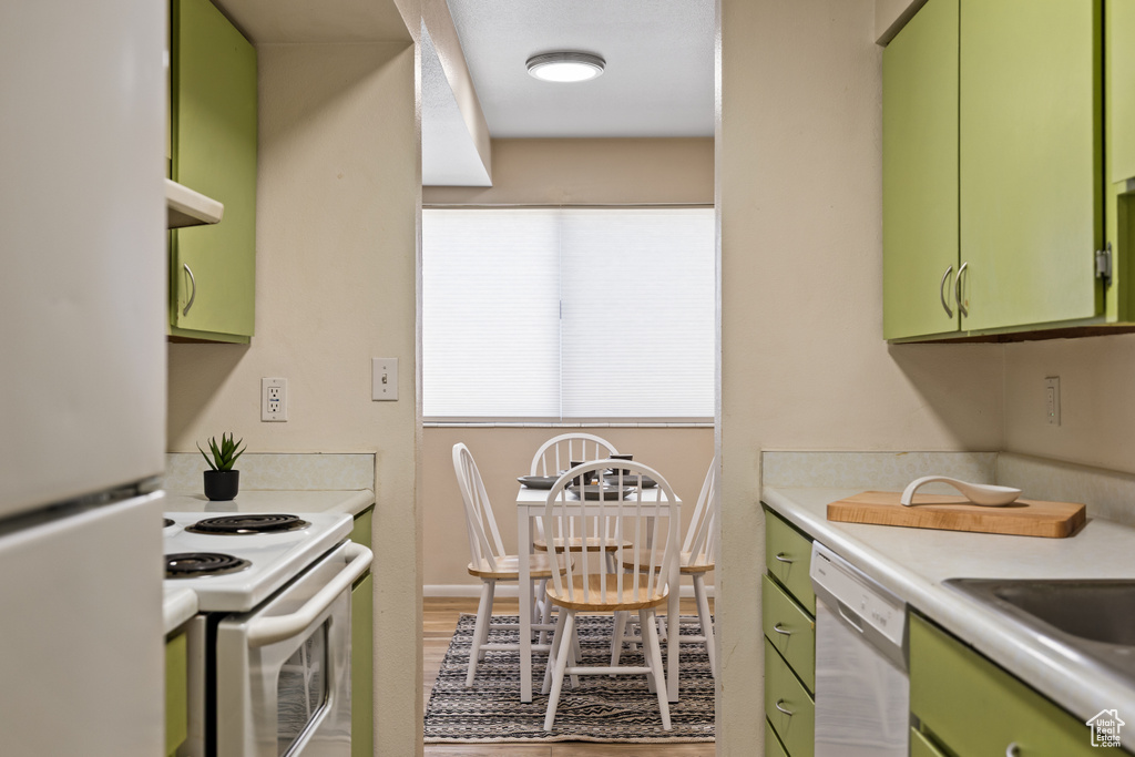 Kitchen with green cabinets, white appliances, and light countertops