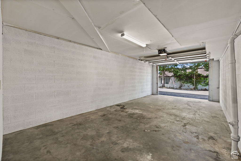 Garage featuring a garage door opener and concrete block wall