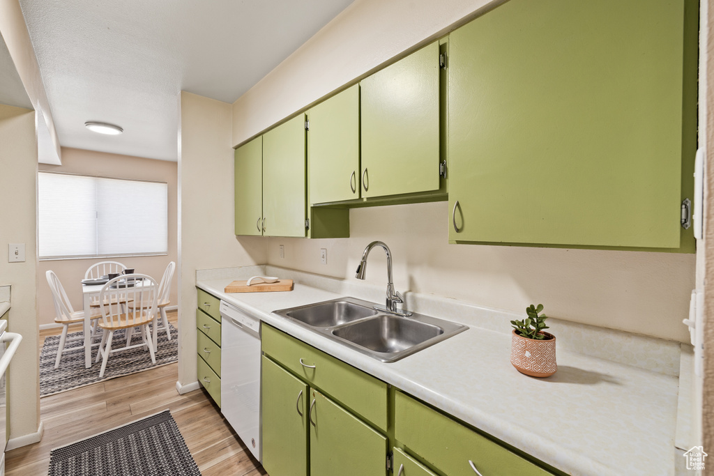 Kitchen with white dishwasher, light countertops, light wood-type flooring, and green cabinets