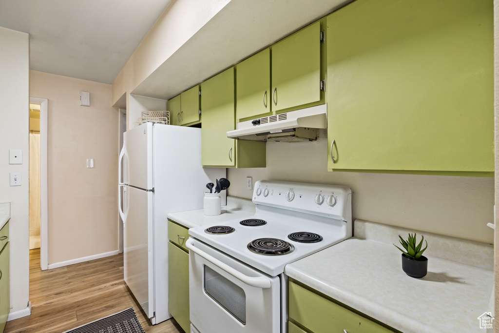 Kitchen featuring white appliances, under cabinet range hood, green cabinets, and light countertops