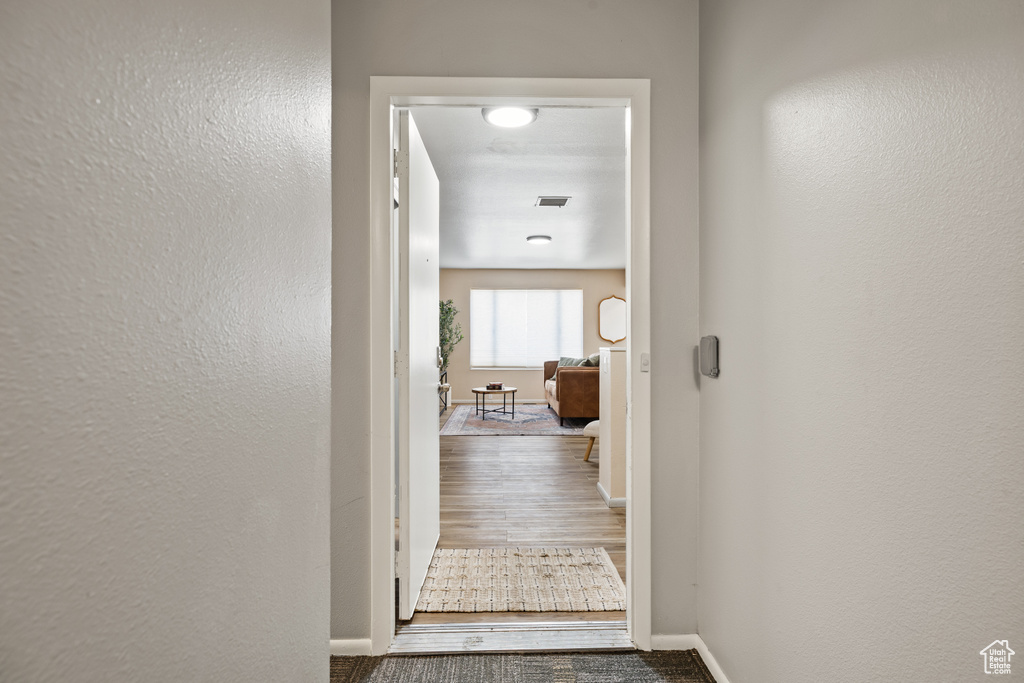 Corridor featuring wood finished floors and a textured wall
