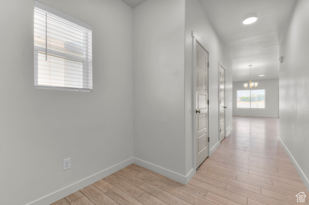 Hallway featuring light wood-type flooring and a chandelier