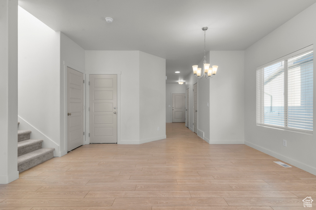 Empty room featuring light wood finished floors, a chandelier, a smoke detector, stairway, and recessed lighting