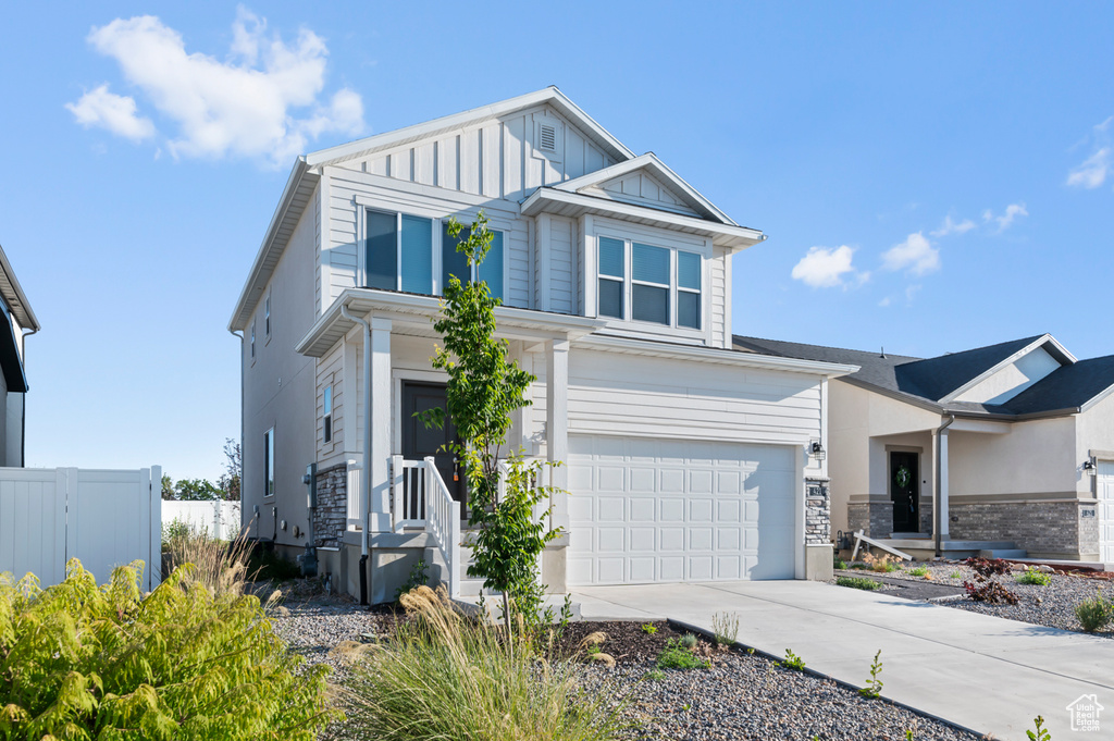 View of front of home featuring an attached garage, driveway, stone siding, and board and batten siding