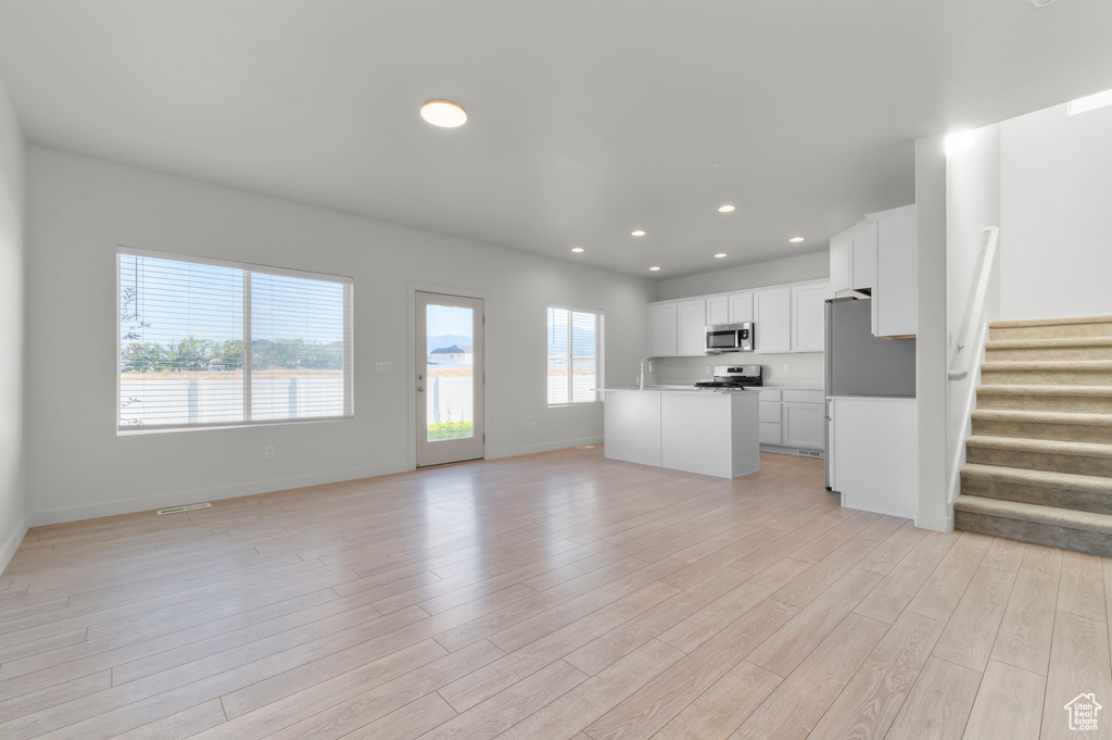 Unfurnished living room featuring light wood-style floors, stairway, and recessed lighting