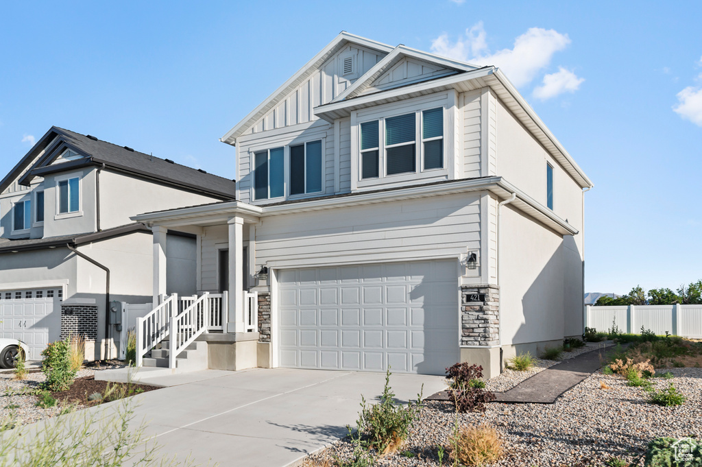 View of front of home with a garage, stone siding, concrete driveway, and board and batten siding