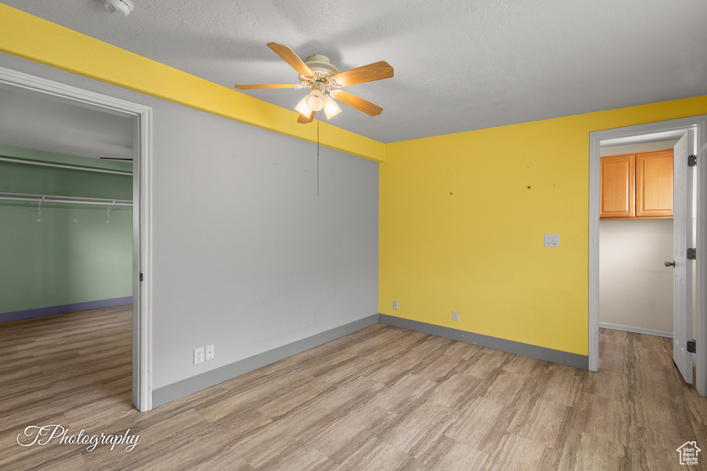 Unfurnished bedroom with light wood finished floors, a ceiling fan, and a textured ceiling
