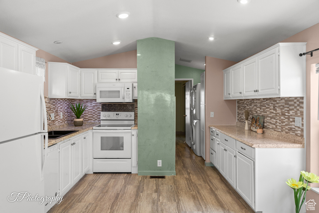 Kitchen with white appliances, lofted ceiling, white cabinetry, light wood-type flooring, and decorative backsplash