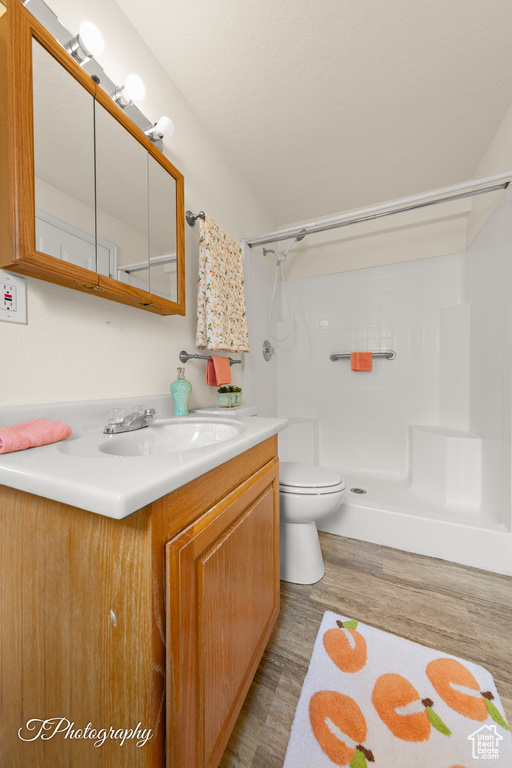 Full bath featuring vanity, a shower, and wood finished floors