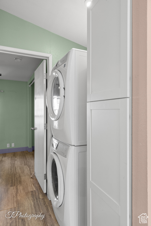 Laundry room featuring stacked washer / dryer and wood finished floors