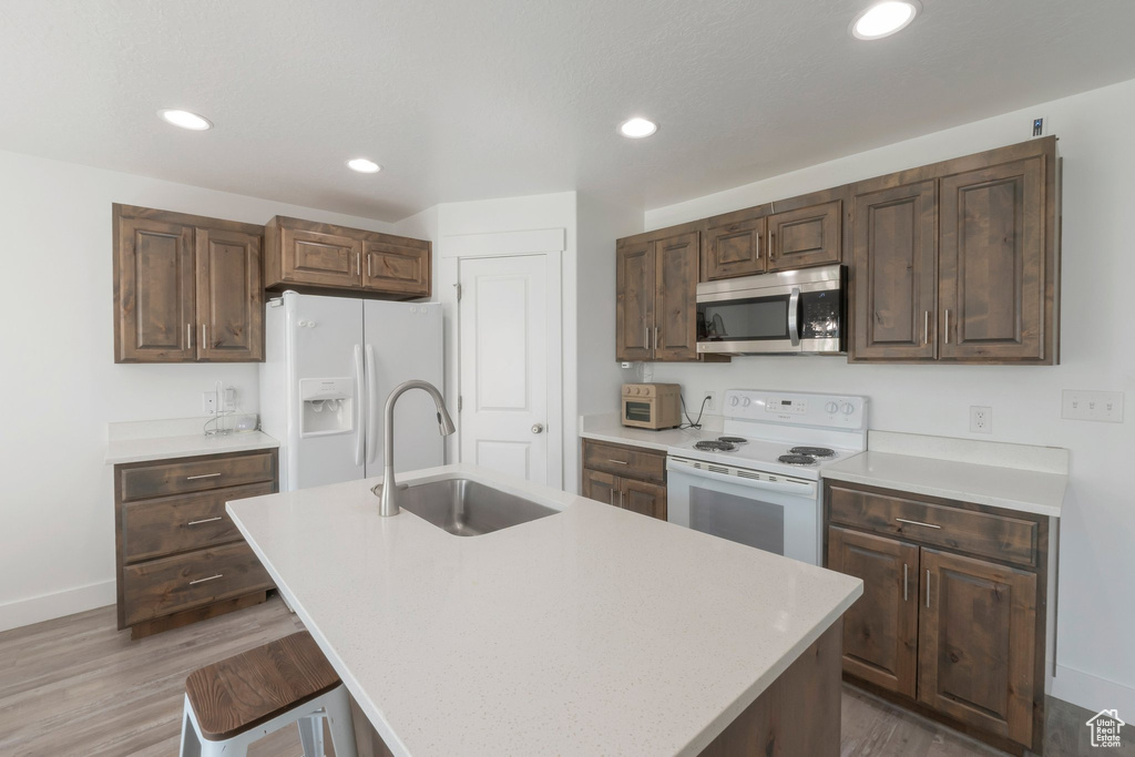 Kitchen featuring white appliances, light countertops, light wood-type flooring, and recessed lighting