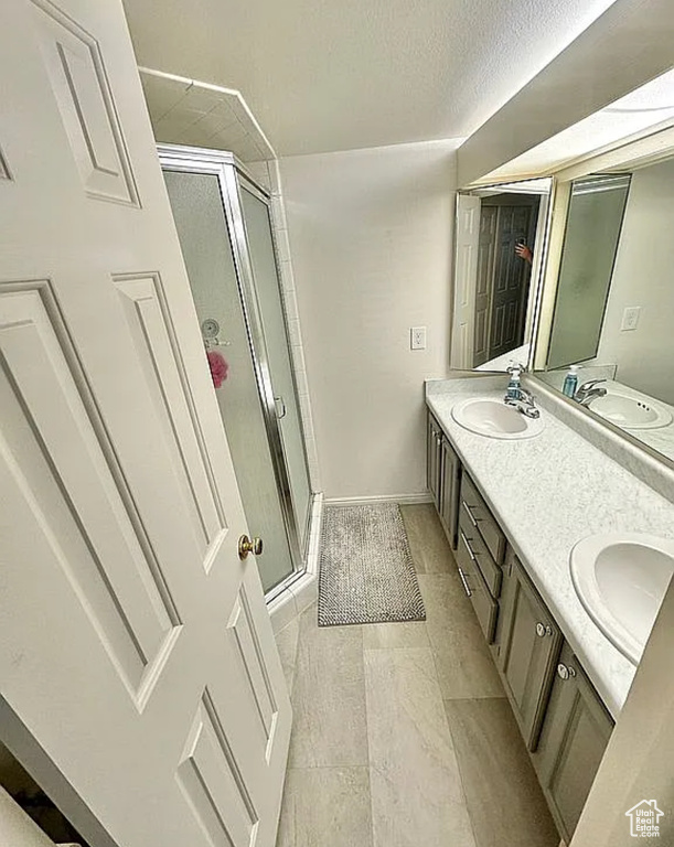 Bathroom with a stall shower, double vanity, and tile patterned flooring