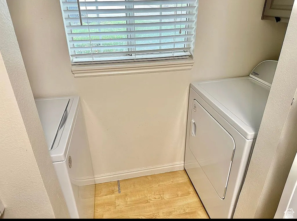 Laundry area with washer and clothes dryer and light wood finished floors