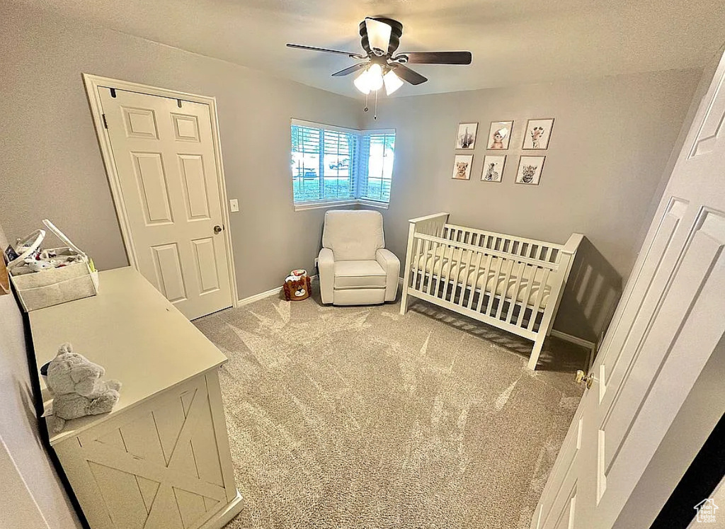 Bedroom with carpet flooring, a crib, and ceiling fan