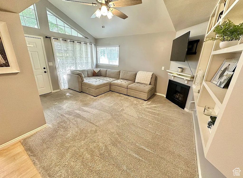 Living area with ceiling fan, a fireplace, and lofted ceiling