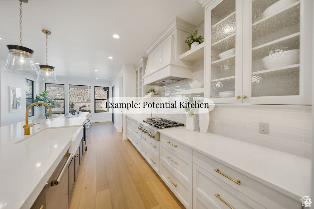 Kitchen with stainless steel gas stovetop, light wood finished floors, tasteful backsplash, white cabinets, and recessed lighting