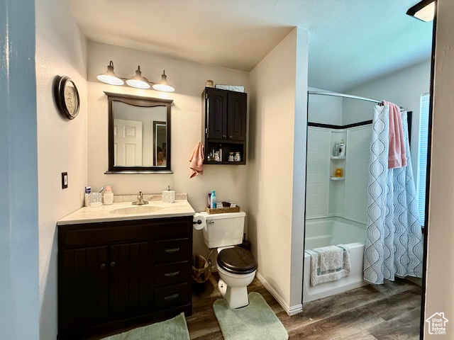 Bathroom featuring wood finished floors, vanity, and shower / tub combo with curtain