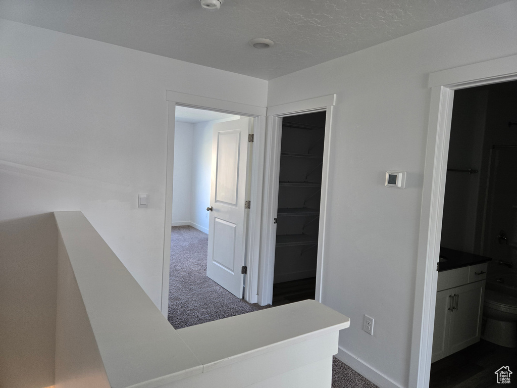 Corridor featuring dark colored carpet and baseboards