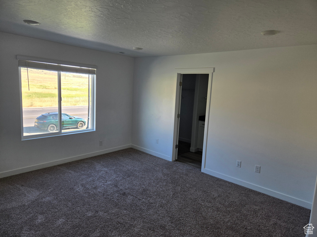 Carpeted spare room with baseboards and a textured ceiling