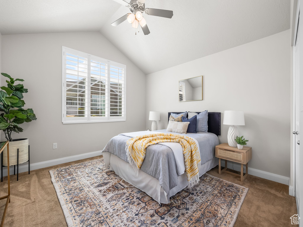 Carpeted bedroom featuring vaulted ceiling and a ceiling fan