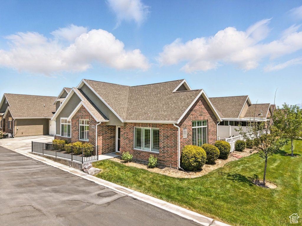 View of front of home with brick siding, roof with shingles, and a front lawn