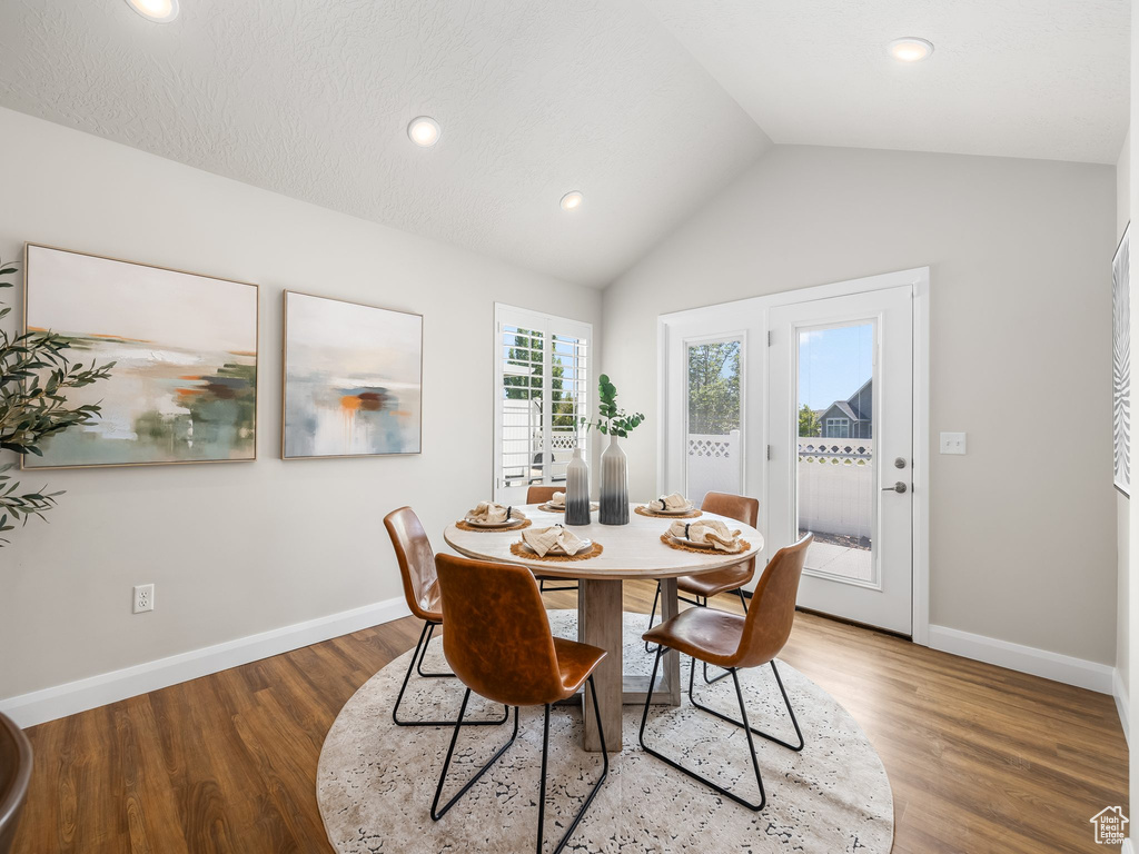 Dining space with wood finished floors, lofted ceiling, and recessed lighting